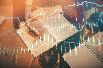 Forex chart hologram on hand taking notes background. Concept of analysis. Multi exposure