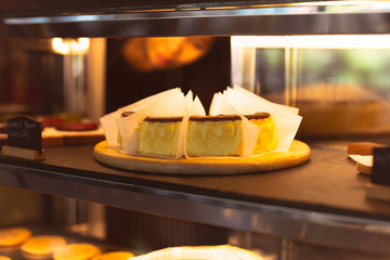 Basque burnt cheesecake in freezer in cafe with waitress in background.
