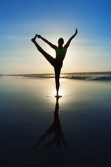 Fototapeta premium Black silhouette of active woman stretching at yoga retreat on sunset beach, sky with sun, ocean surf background. Travel lifestyle, people outdoor activity, family summer vacation on tropical island.
