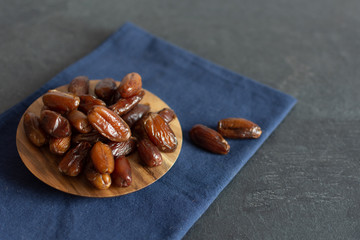 Bowl of dried dates on wooden background with space for text.