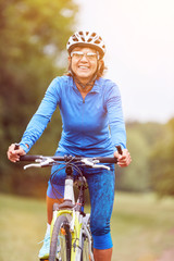 Obraz premium Ältere Frau beim Fahrrad fahren mit Mountainbike