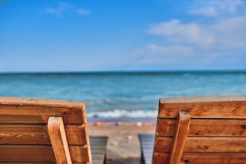 Fototapeta premium Sunbeds on the beach. Two wooden chairs for relaxing on the lake shore.