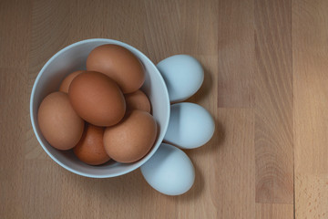 several fresh chicken eggs in a ceramic cup on a wooden background. Healthy eating concept