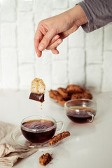 Hand putting tea paper bag into the cup. Preparing tea concept.