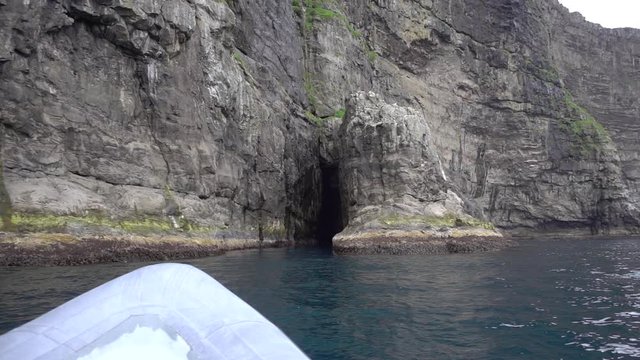 outboard boat approaching to cave in the wall