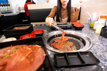 asian women Use Meat tong pick up the meet in a BBQ restaurant