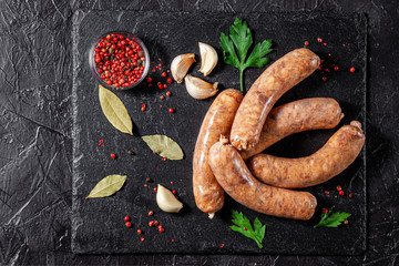 The concept of farm, organic products. Raw homemade pork barbecue sausages on a black slate board....