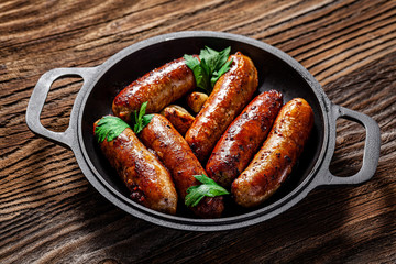 The concept of farm, organic products. Homemade grilled pork barbecue sausages in an iron pan. background image. copy space