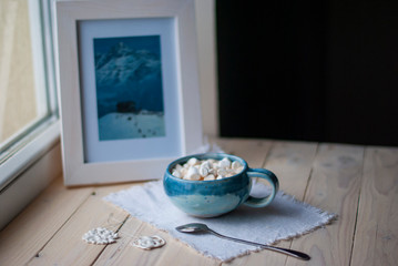 A cup of cacao with marshmellows and christmas decoration on the table with colorful background. Chistmas holiday background. Phantom Blue.