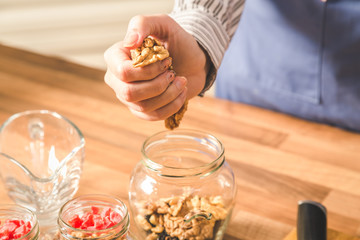 Close-up of woman using walnuts while preparing food.