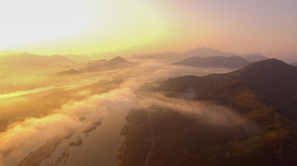 Fototapeta premium Autumn landscape high angle aerial drone shot. Above Fog or mist over beautiful colorful woods landscape.