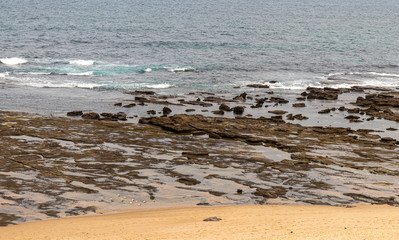 Sydney, Australia, New South Wales, 12/15/2019. Norah Head Beach with a beautiful natural construction of stones forming a path as if receiving a boat. It resembles a pier. There some mountains around