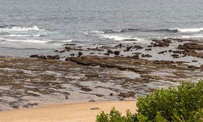 Sydney, Australia, New South Wales, 12/15/2019. Norah Head Beach with a beautiful natural construction of stones forming a path as if receiving a boat. It resembles a pier. There some mountains around