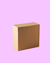 Side view of square closed Kraft cardboard box. The box is carved on a pink background.