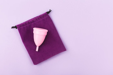 Menstrual cup and elegant bag on pink background. Flatlay, top view. Copy space for your text.