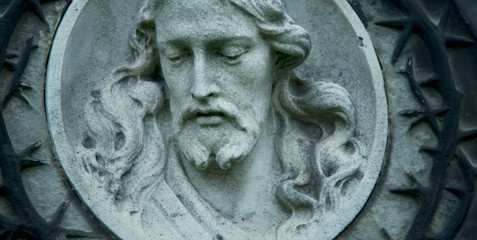 Jesus Christ antique statue against a background of gray stone.