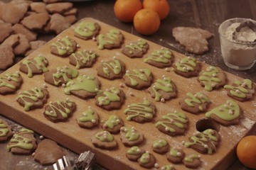 Freshly baked Christmas ginger cookies coated with green sugar glaze and pearl balls on a wooden board