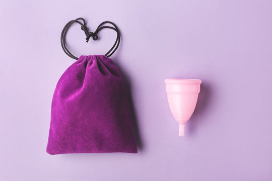 Menstrual cup and elegant bag on pink background. Flatlay, top view. Copy space for your text.