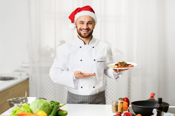 Chef Man In Santa Hat Presenting Dish Standing In Kitchen