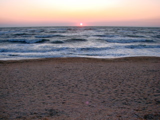 Panorama of the coast of the Azov Sea covered with white foam morning waves at dawn.