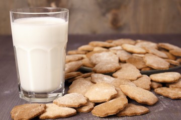 Transparent glass cup with milk and ginger spicy cookies on a wooden table