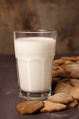 Transparent glass cup with milk and ginger spicy cookies on a wooden table