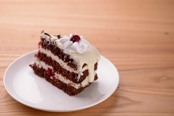 Chocolate vanilla cake with cherry jelly, topped with white cheese frosting and chocolate pieces