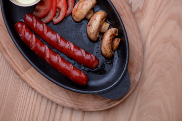 Mix breakfast dinner lunch supper with mushrooms, tomatoes and sausages served on a black plate