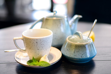 Blue and white tea set with mint and a slice of lemon on dark wooden table.