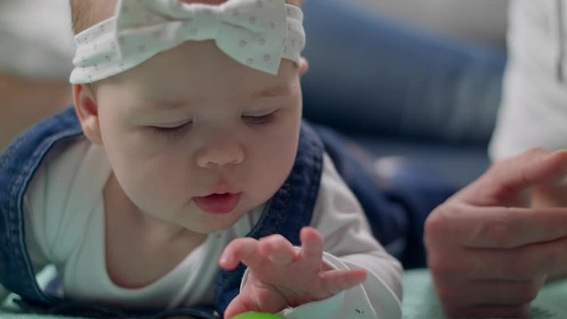Little girl kid plays a rattle on the floor with parents