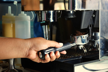 The hand of the barista is making coffee.