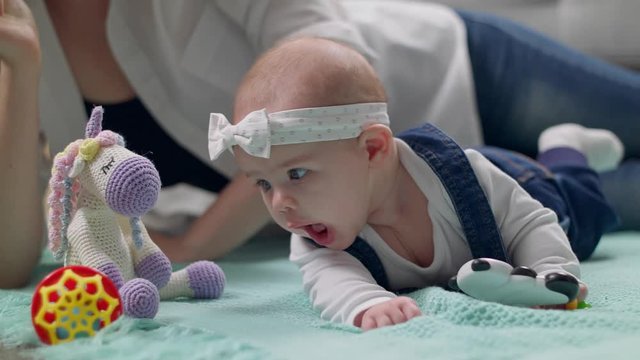 Little girl kid plays a rattle on the floor with parents