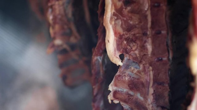 Ham and bacon hanging and drying in smokehouse on traditional way on blue smoke.  The sunrays pierce through the blue smoke.