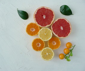 Fresh citrus fruits. Grapefruit, lemon, clementines, mandarin and green leaves on a textured white background. Top view, flat lay. 