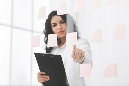 Hispanic businesswoman making notes on glass wall