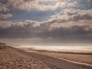 Empty Strandhill beach, county Sligo, Ireland, Dramatic cloudy sky with sun rays, Warm and cool tones,