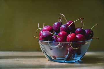 Fresh cherry glass bowl ready to serve. On a light-coloured wooden background, perfect for adding text