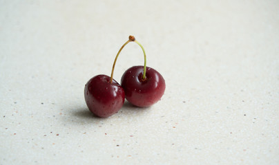 Two isolated raw cherries on a marble table base with an empty copy space for text, selective focus and toned image.