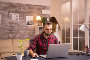 Focused bearded entrepreneur working on laptop from home