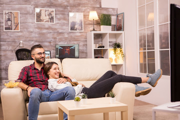 Beautiful young couple relaxing on sofa while watching a movie on tv