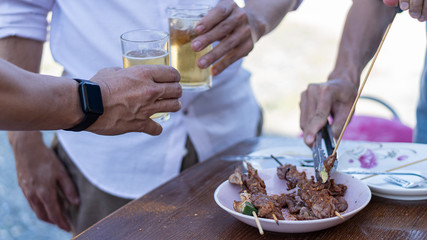 3 men celebrate the new year by beating beer, barbeque on the table, enjoying beer during the new year.