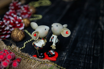 Pair of toy mice or rats on wooden black background with pine branches and red painted cones. Chinese New Year symbol. Place for text.