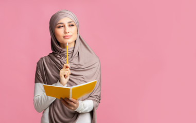 Pensive muslim girl holding notepad and pencil, thinking about something