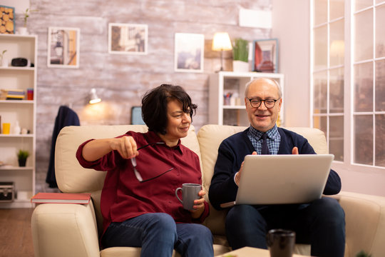 Elderly old couple using modern laptop to chat with their grandson