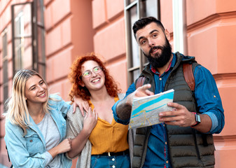 Obraz premium Group of tourists enjoying on vacation, young friends having fun walking on city street during the day.