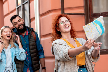 Group of tourists enjoying on vacation, young friends having fun walking on city street during the day.