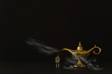 Concept picture of a businessman looking at Aladdin lamp with smoke, asking for a wish