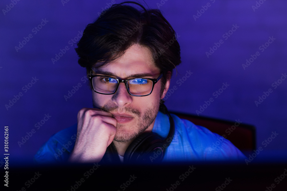 Poster serious concentrated developer working on computer at night