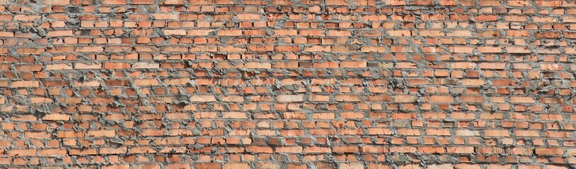 Red bricks wall texture and background. Panorama. The fragment of bad and dirty bricklaying with cement smeared bricks. Сonstruction of a new multistory building. Construction site