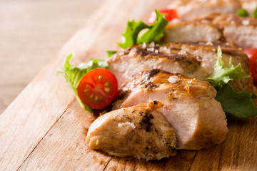 Grilled chicken breast with vegetables on wooden table